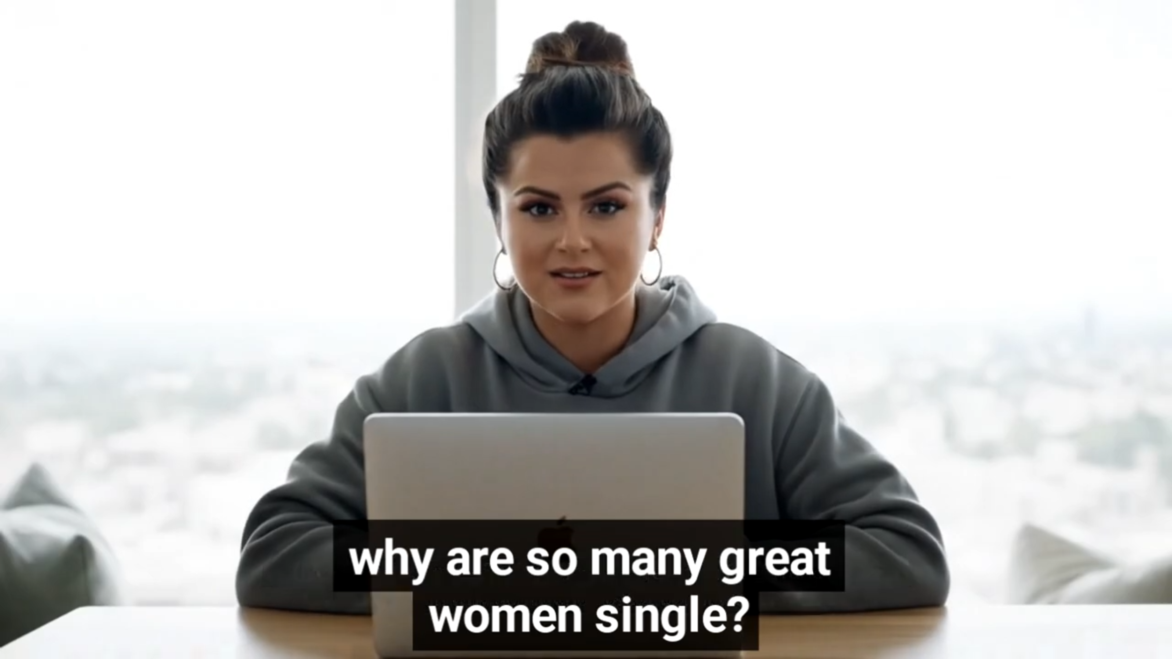 A woman wearing a gray hoodie sits in front of a laptop. The caption reads &quot;Why are so many great women single?&quot;
