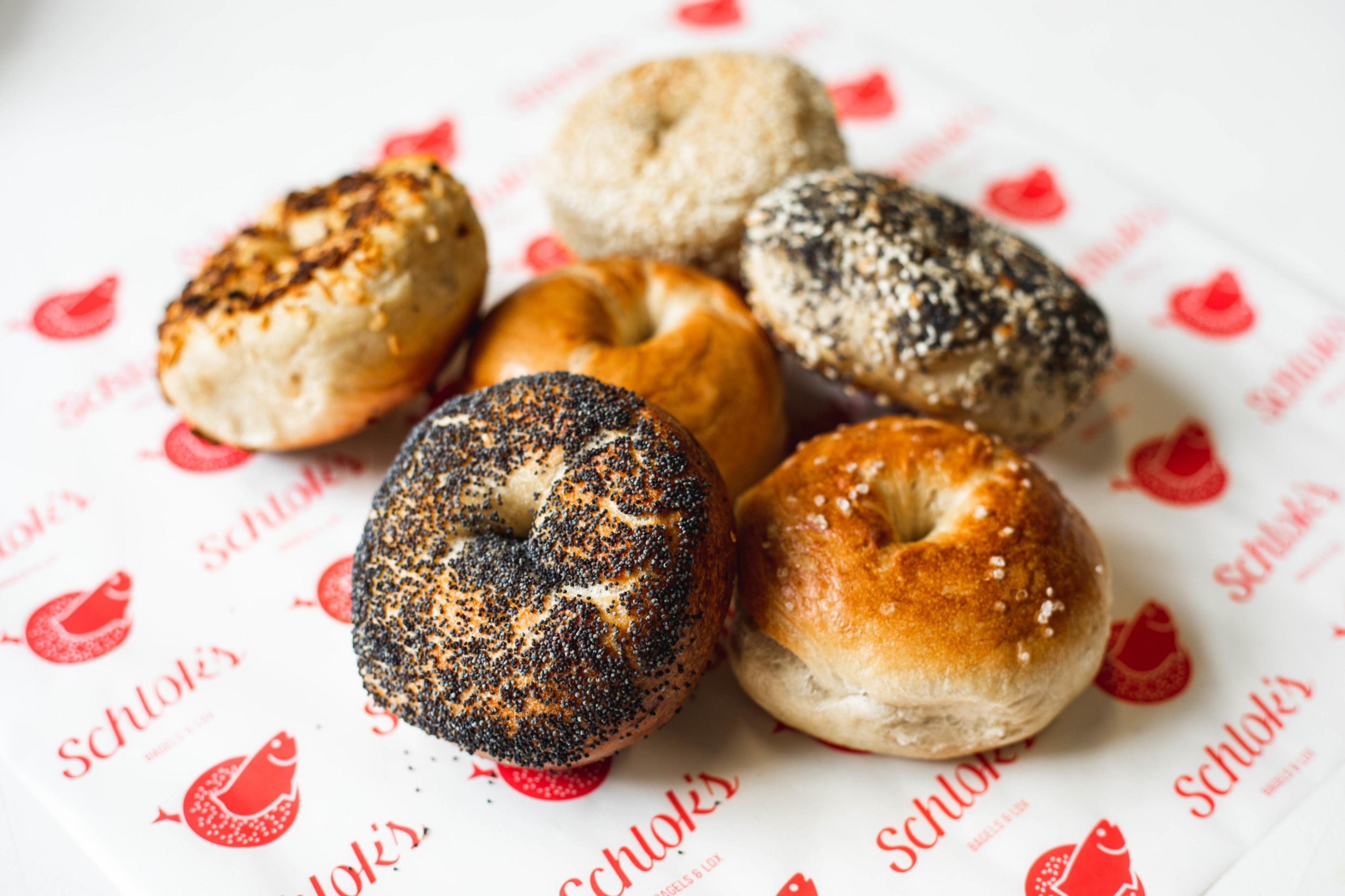 A half dozen bagels including poppyseed, salt, and plain sit on a piece of Schlok's wax paper.