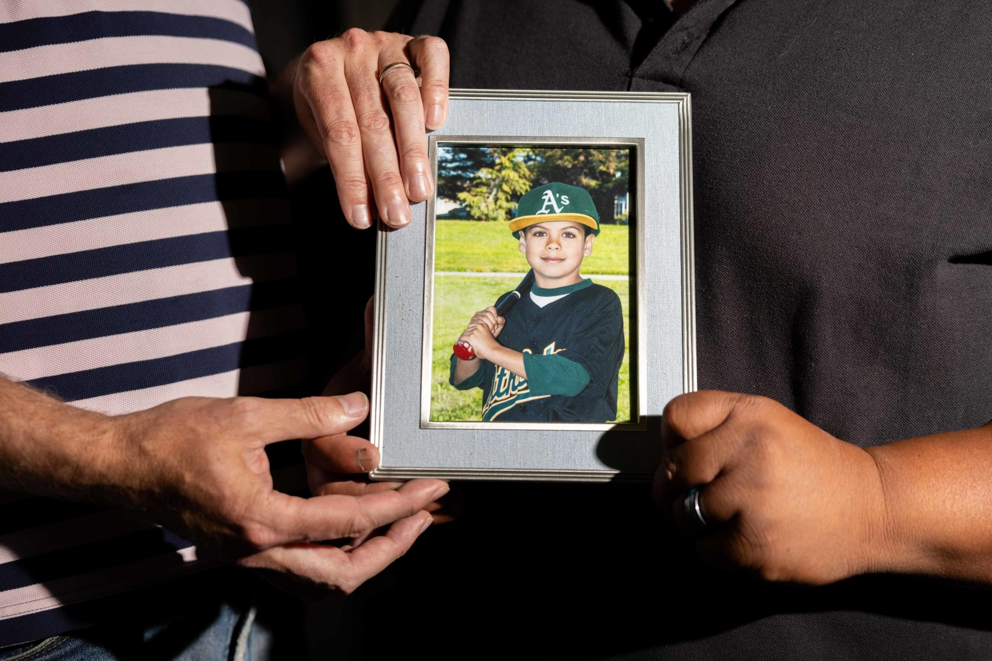 Degala and Burnett hold photo of Caleb as child