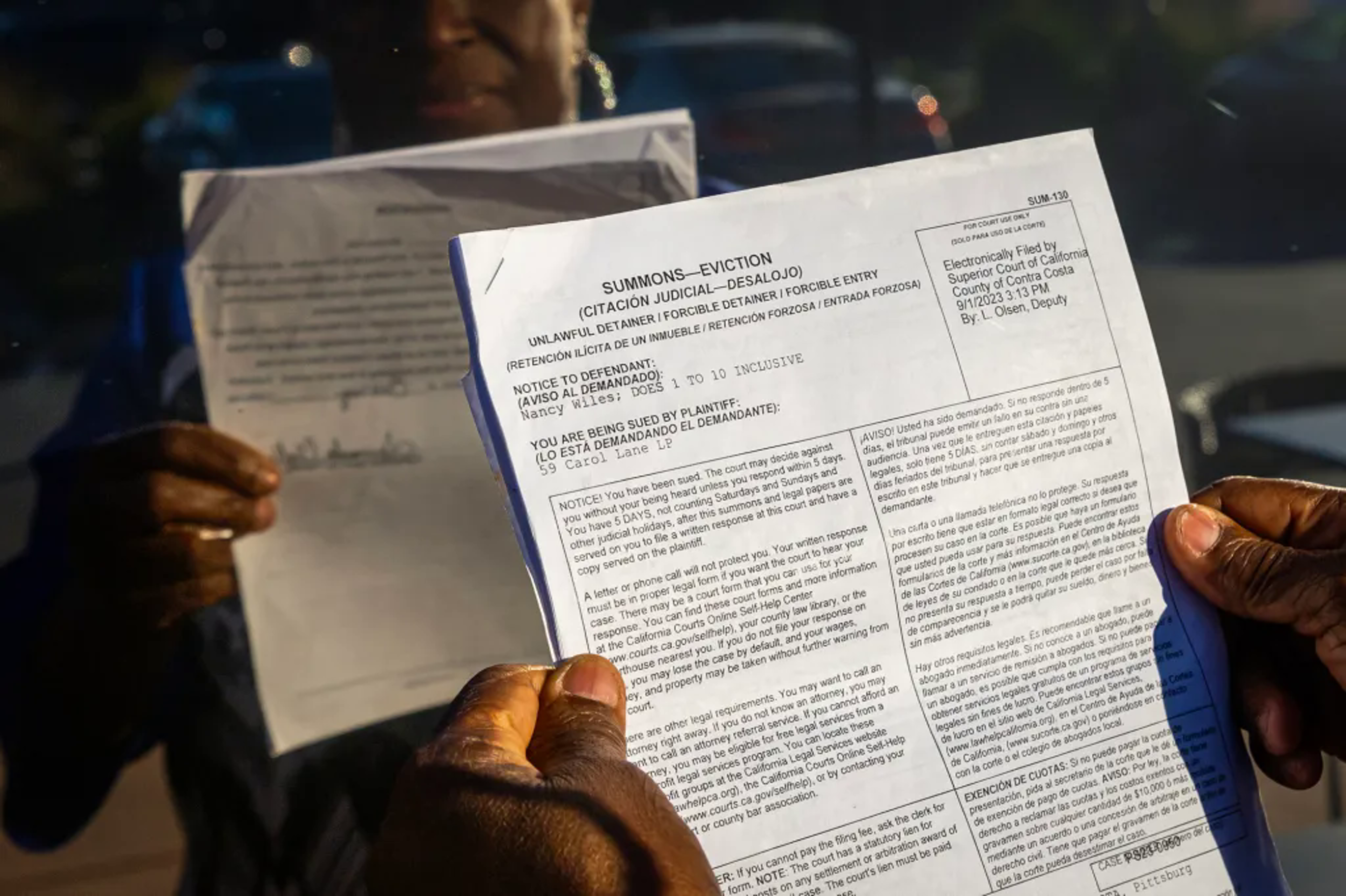 A woman holds up a copy of an eviction notice
