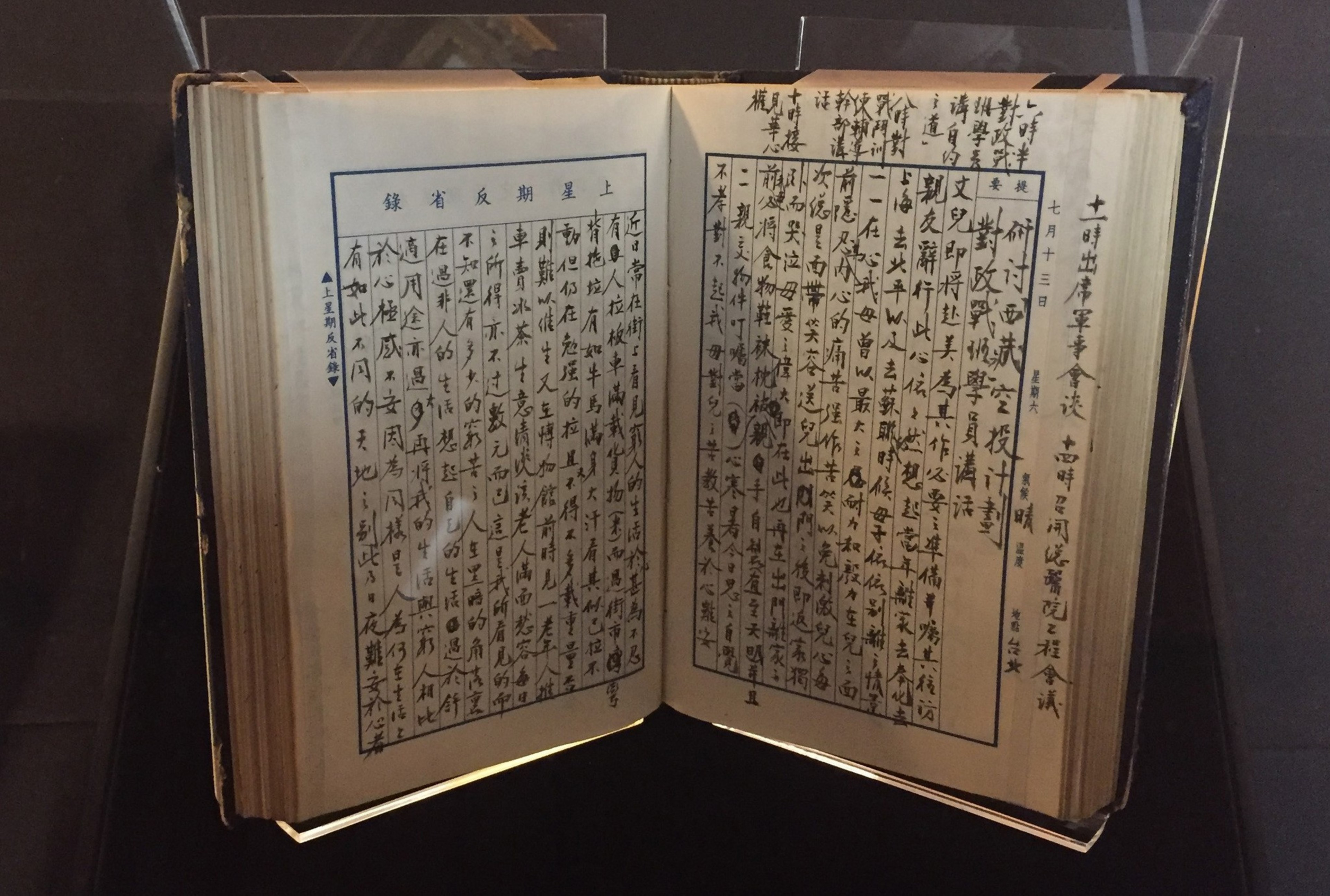 An open book displayed under glass contains handwritten text in vertical columns of traditional Chinese characters, neatly arranged on both pages.
