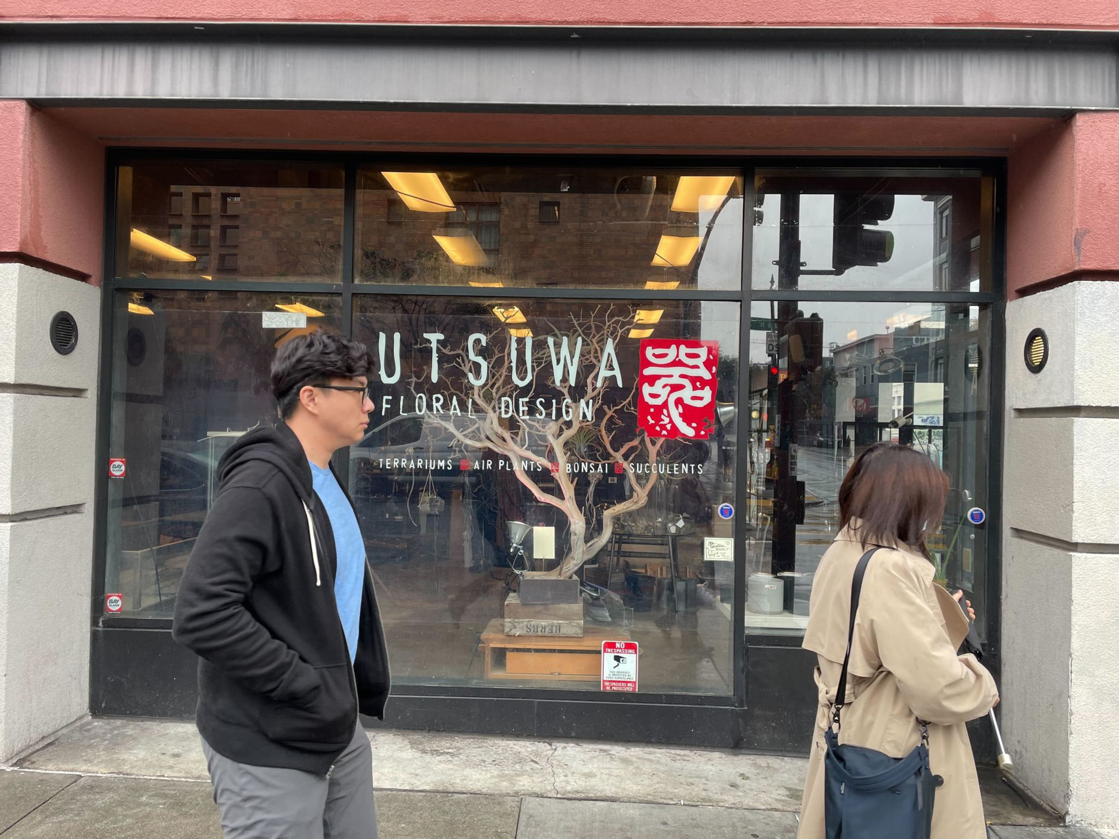 the exterior of a japanese plant store is seen as people walk by